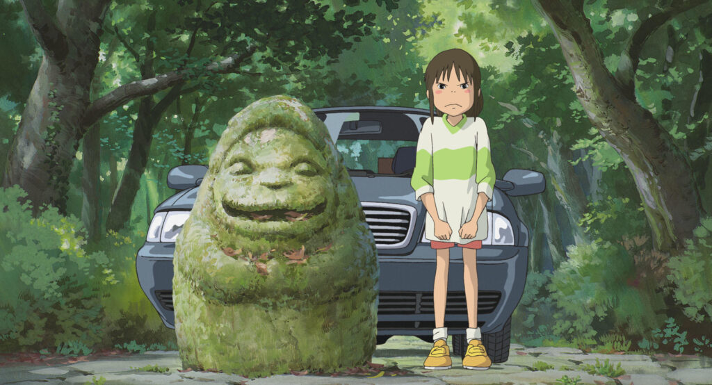 Still from Spirited Away: Chihiro stands in front of a car and next to a moss-covered stone statue in a forest.