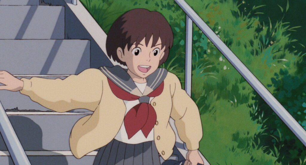 Still from Whisper of the Heart: An animated girl in a school uniform walks down outdoor stairs, holding the handrail, with greenery in the background, illustrating the theme of Japanese school life as seen in Ghibli movies.